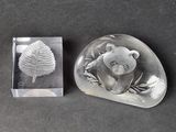 a glass object with a bear on it next to a leaf
