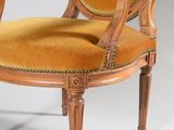 an old chair with a yellow upholstered seat and wooden legs