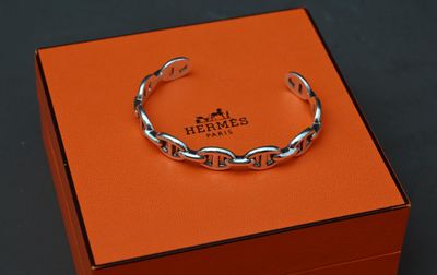 une boîte orange sur laquelle est posé un bracelet argenté