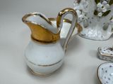 a white and gold vase with a gold top and a white and gold pitcher with a gold top