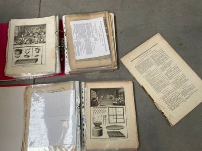Plusieurs vieux livres sont posés sur une table recouverte d'une nappe rouge.