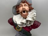 statue of a man with a beard wearing a hat and a red bow