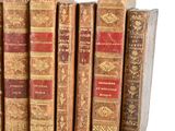 several old books are stacked on top of each other on a shelf