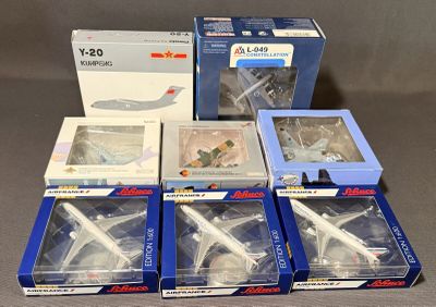 Plusieurs maquettes d'avions sont rangées dans des boîtes posées sur une table