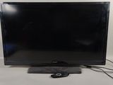 La télévision à écran plat est posée sur la table devant le mur.