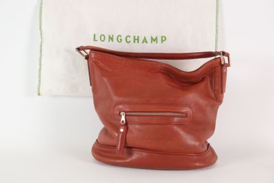 Le sac Longchamp est posé à côté d'un sac blanc et d'une serviette blanche.