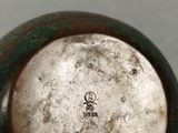 a silver and green vase sitting on a table