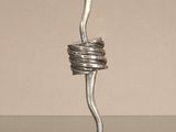 une sculpture métallique en forme de spirale posée sur une table en verre