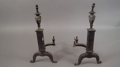 Paire de chenets en fer forgé surmontés de vases couverts ba…