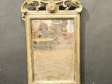 un miroir accroché au mur, avec une chaise à l'arrière-plan