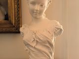 une busturine blanche posée sur une table devant un tableau