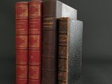 three books are stacked on top of each other on a black surface