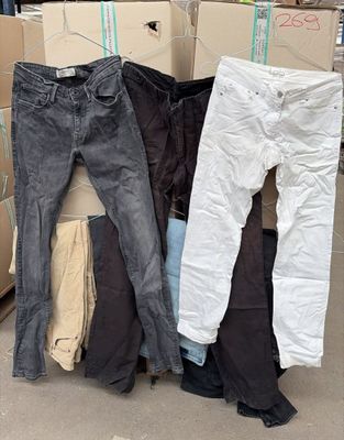 Plusieurs paires de jeans sont empilées sur des cartons dans un entrepôt