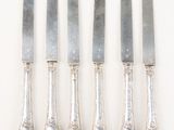 six silverwares and a knife on a white table