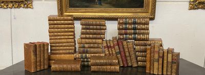 de nombreux livres posés sur une table, avec un tableau en arrière-plan