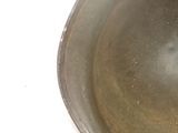 a metal bowl with a spoon in it on a white surface