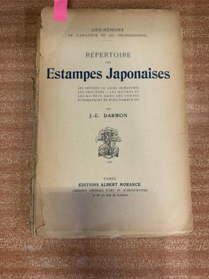 un vieux livre posé sur une table en bois, à côté d'un marqueur rose