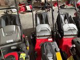 Plusieurs tondeuses à gazon sont alignées en rang dans un garage
