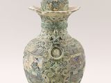 an old green vase with a bird on top of it