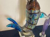 a blue table topped with glass figurines of birds and fish