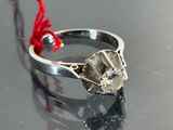 une bague en argent sertie d'un diamant, posée sur une table