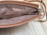 the inside of a brown purse with a handle on a wooden floor