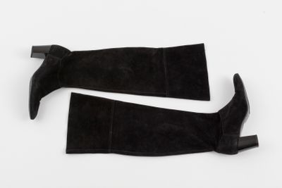 une paire de bottes en daim noir posées sur une surface blanche