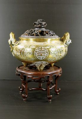 un grand bol en laiton posé sur un socle en bois orné d'un dragon