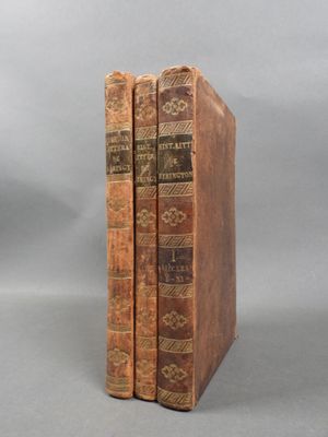 two old books sitting on top of each other on a gray surface