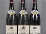Trois bouteilles de vin sont alignées sur une table en verre
