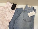 two pairs of jeans are sitting on a table with a tag