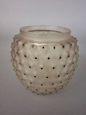 un vase blanc parsemé de points noirs, posé sur une table