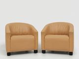 une paire de fauteuils en cuir beige aux pieds noirs, sur fond blanc