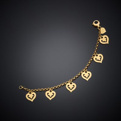 a gold bracelet with heart charms on a black background