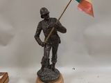 figurine of a soldier holding a flag on a wooden base