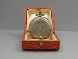 une petite boîte rouge contenant une montre de poche en argent