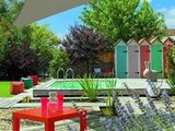une table rouge posée sur une terrasse en bois près d'une piscine