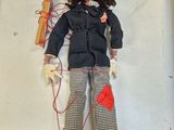 une poupée avec un nez rouge, une veste noire et un pantalon noir