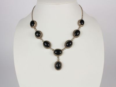 a necklace with black beads and a silver chain on a mannequin