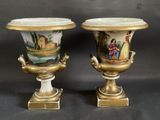 pair of vases with painted scenes on them sitting on a table