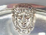 a silver plate with a face on it on a table