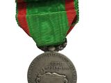 an old medal with a red and green ribbon on a white background