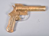 a gold gun that is sitting on a white table