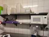 a microwave and a fan in a small kitchen