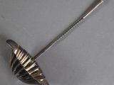 an antique silver spoon with a handle on a gray surface