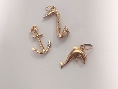 deux breloques en forme d'ancre et de dauphin dorées sur un fond blanc
