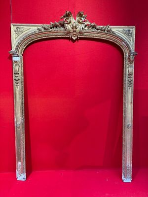 un encadrement de cheminée richement sculpté, avec un mur rouge en arrière-plan