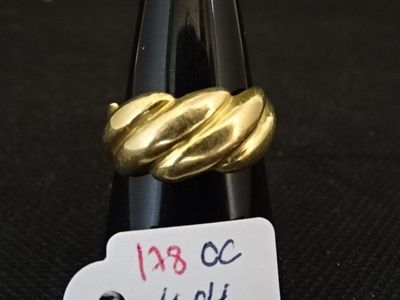 une bague en or posée sur une bouteille de vin