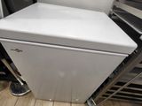 un réfrigérateur blanc posé dans une cuisine, à côté d'une rangée d'étagères