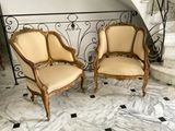 une paire de chaises anciennes de style français posées sur un sol en marbre, devant un escalier en colimaçon